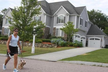 A 2013 photo of a woman walking her dog past the North Attleboro house owned then by Aaron Hernandez.
